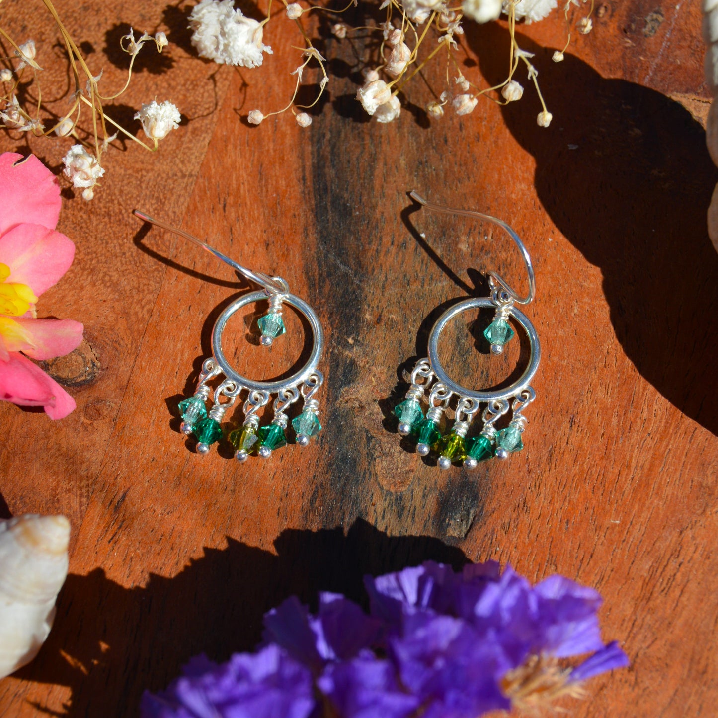 A pair of silver hoop dangle earrings with green and turquoise Czech faceted bicones.