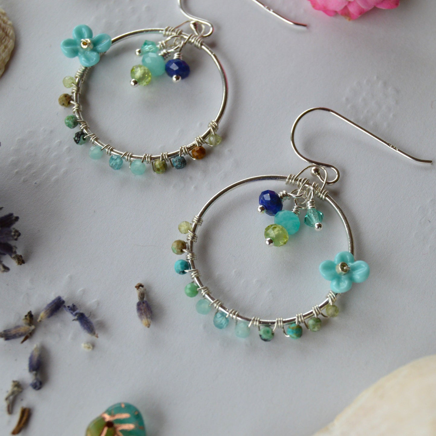 Hoop earrings in Sterling Silver wire-wrapped with gemstones, Czech glass faceted crystals, and lampwork beads crafted as flowers.