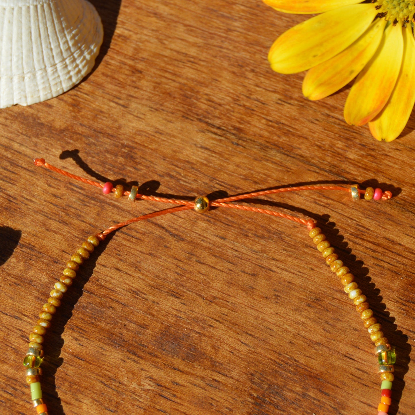 Adjustable, floral seed beads bracelet with silicone stopper bead on nylon cord.