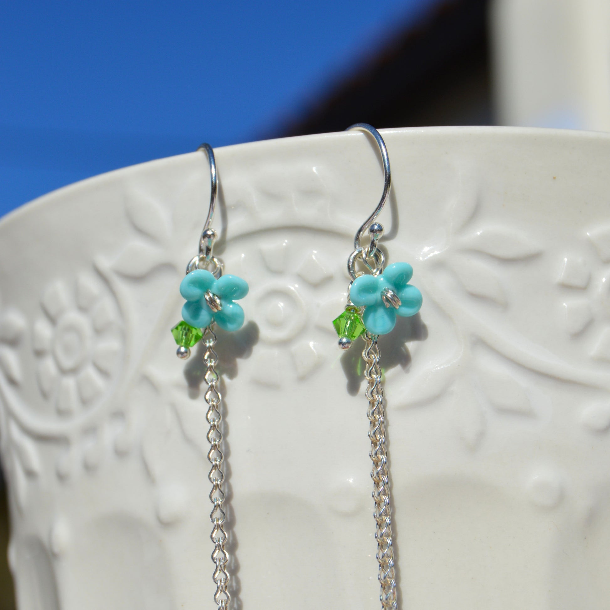 Sterling silver earring featuring Czech glass bead in green, lampwork flower and Czech glass faceted bicone.