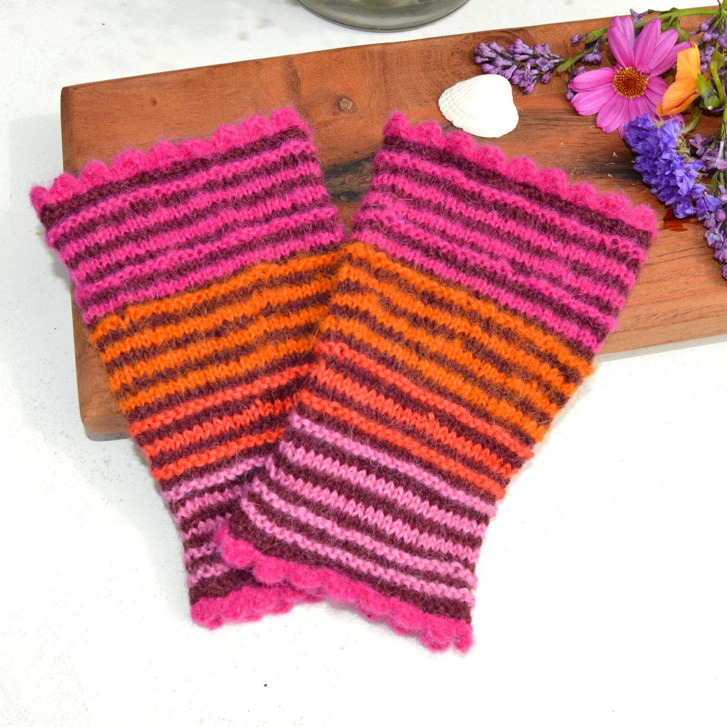 Knitted pulse warmers in alpaca wool in bordeuax colour with contrasting stripes in pink and orange tones.