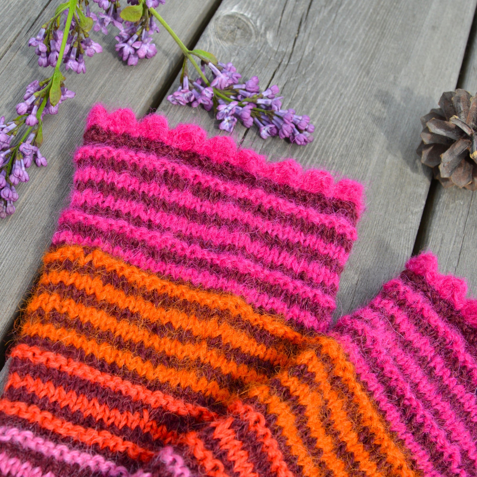 Knitted pulse warmers in alpaca wool in bordeuax colour with contrasting stripes in pink and orange tones.