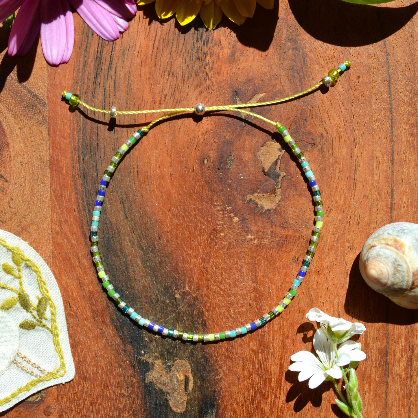 Adjustable, colourful beaded bracelet in green and blue tones.