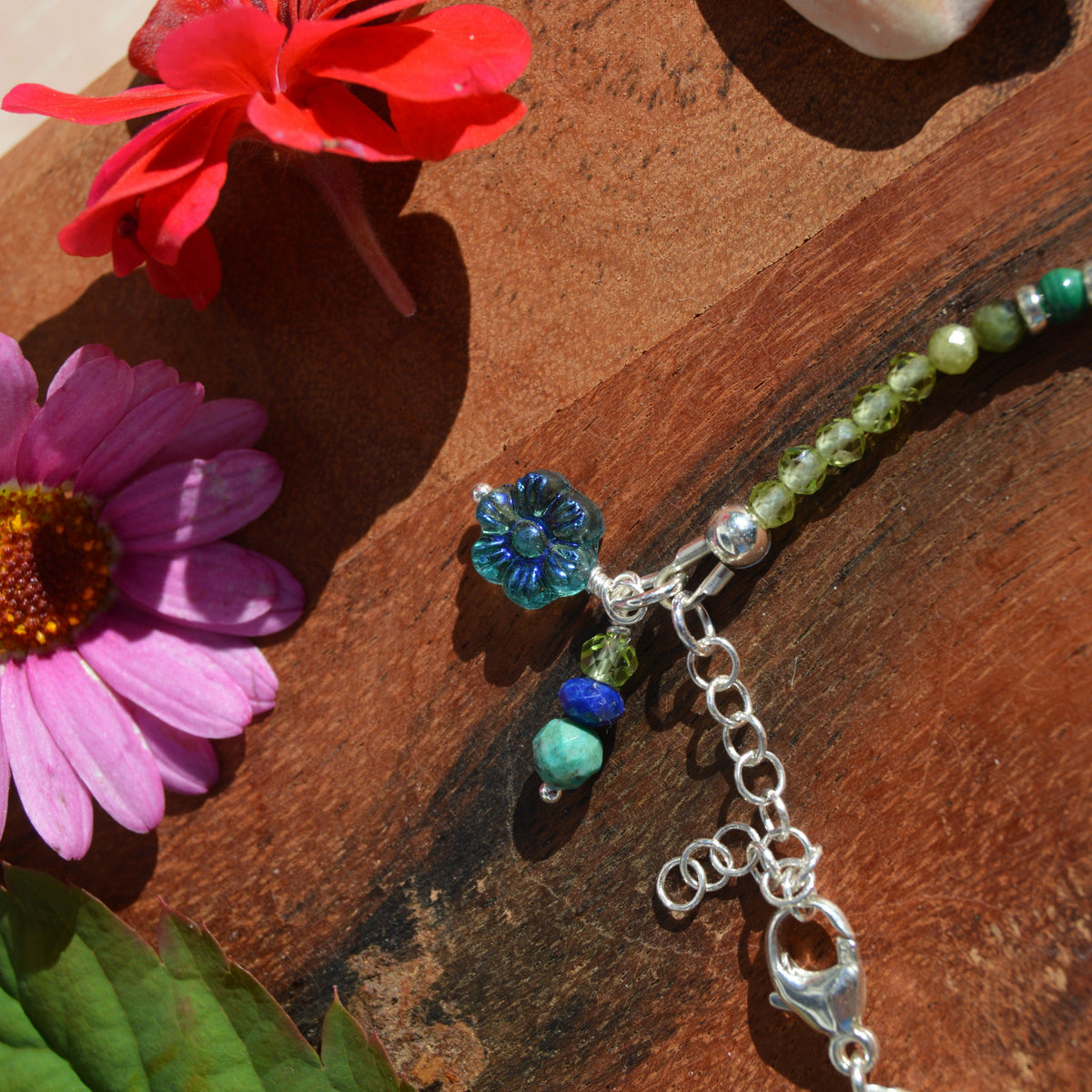 Gemstone bracelet in sterling silver in violet, blue, and green tones. Blue glass flower.