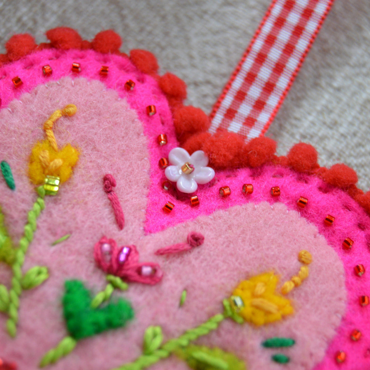 Embroidered Wool Folklore Heart with flower motif, decorated with glass seed beads. A lampwork glass flower bead.