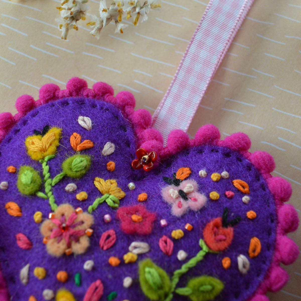 Embroidered Wool Folklore Heart with flower motif, decorated with glass seed beads. A lampwork glass flower bead.