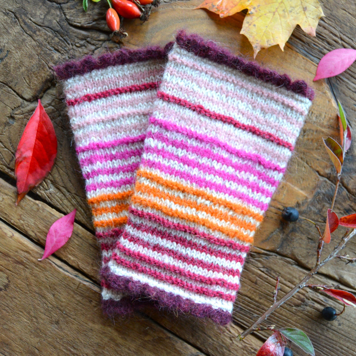 Pulse warmers in alpaca wool in beige and light and neon pink, orange, and raspberry stripes. Bordeaux crochet edge.