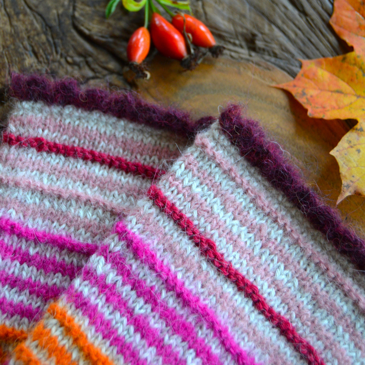 Pulse warmers in alpaca wool in beige and light and neon pink, orange, and raspberry stripes. Bordeaux crochet edge.