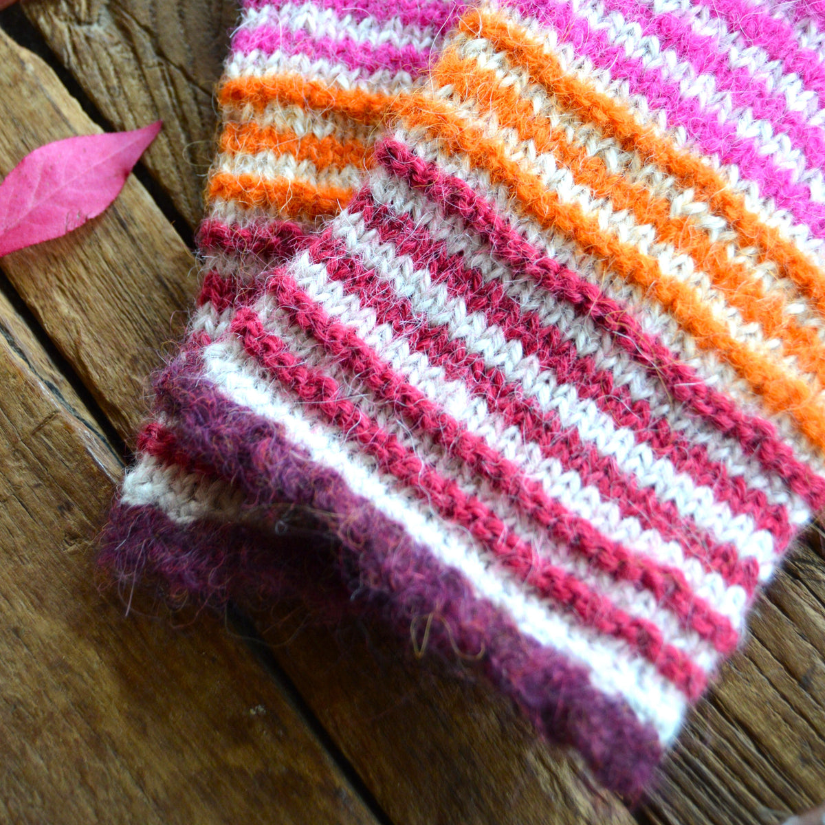Pulse warmers in alpaca wool in beige and light and neon pink, orange, and raspberry stripes. Bordeaux crochet edge.