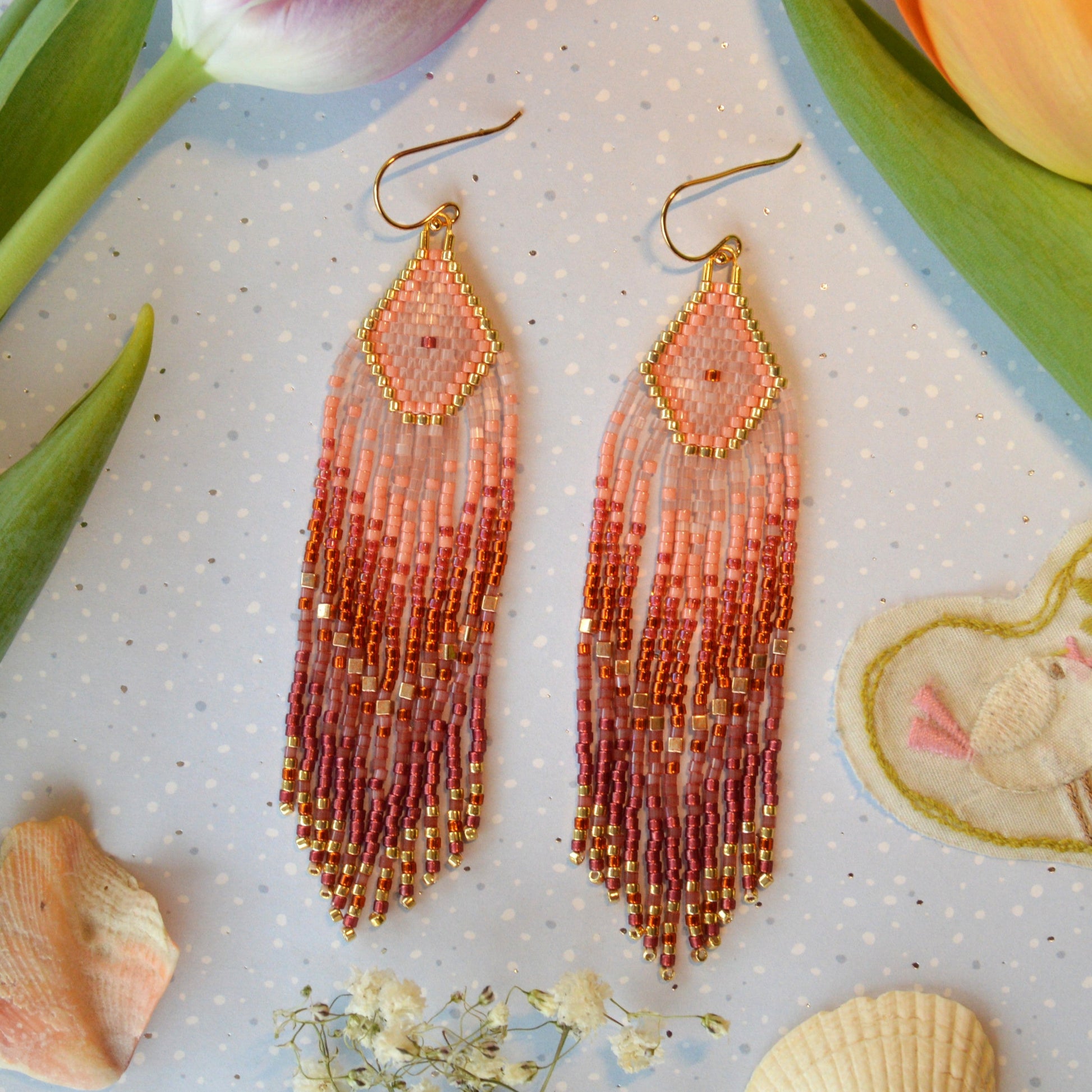 Dreaming Big long fringe earrings made of high quality Japanese seed beads in pink, dark orange, and shades of bordeaux colour combined with gold.