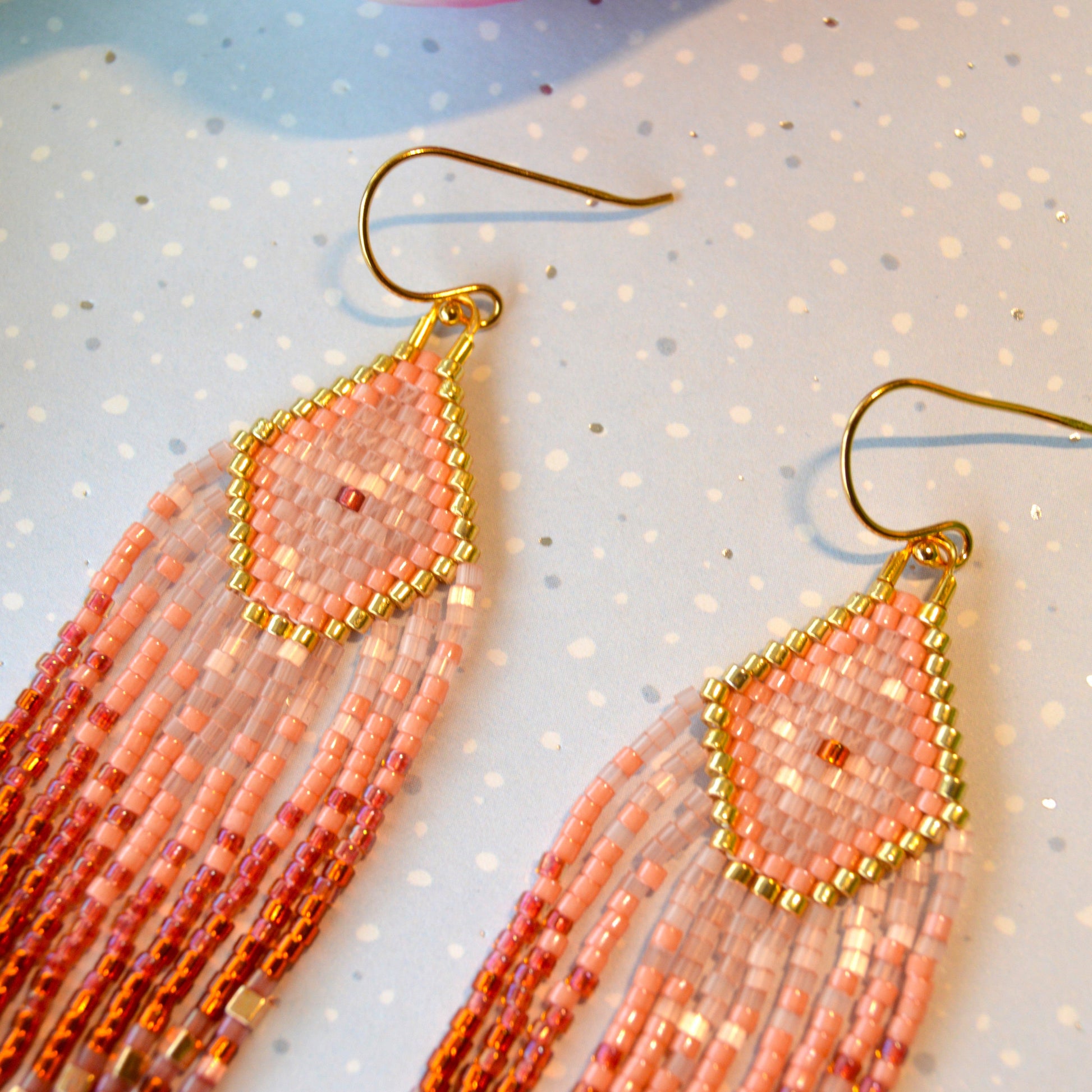 Dreaming Big long fringe earrings made of high quality Japanese seed beads in pink, dark orange, and shades of bordeaux colour combined with gold.