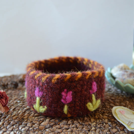 Small crochet basket with embroidered flowers.