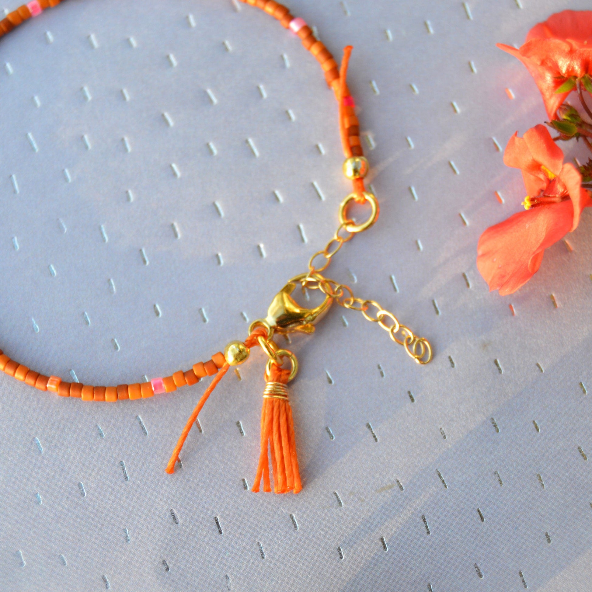 Boho beaded bracelet with a little tassel in orange colour.