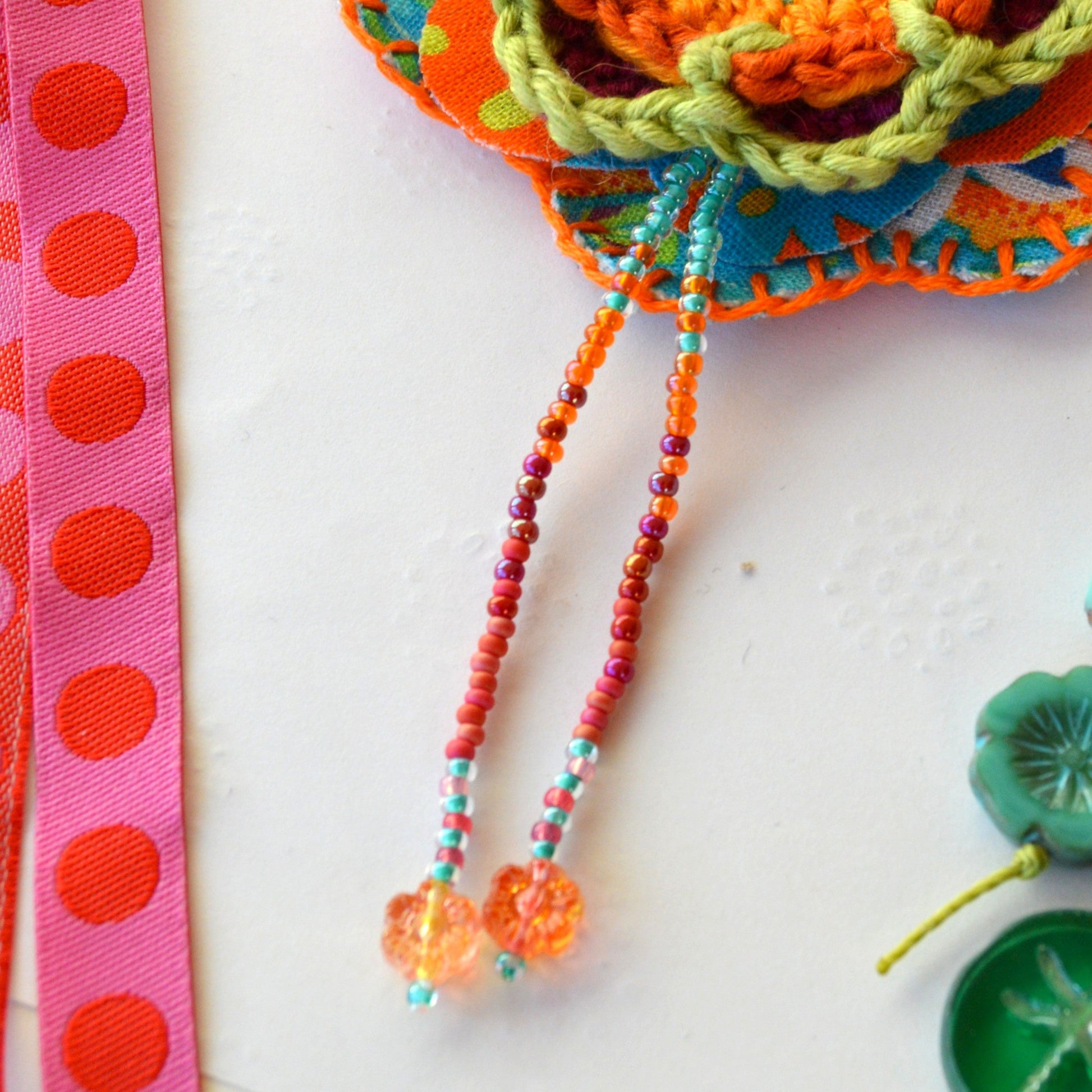 Handbag charm with crochet and fabric flowers decorated with seed beads.