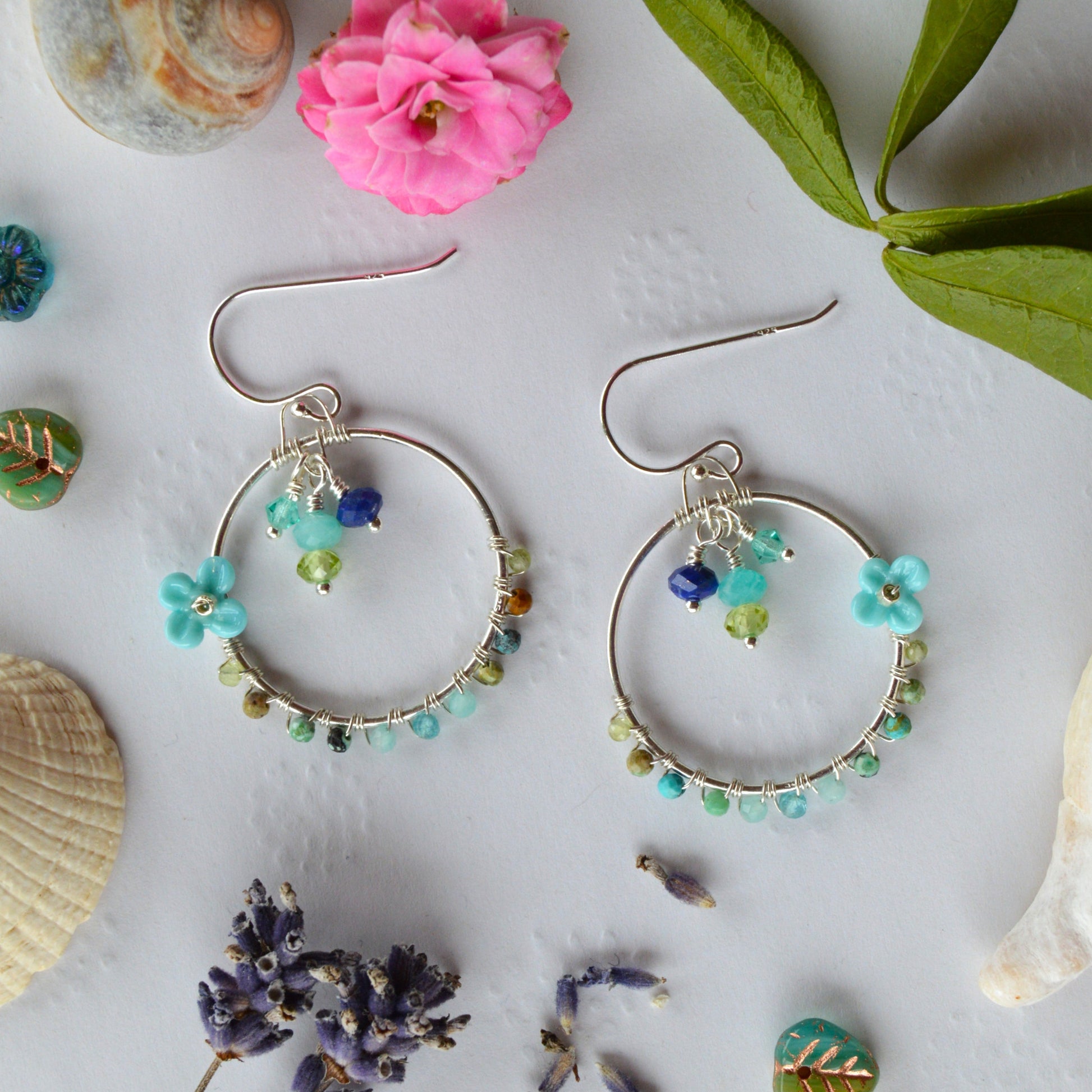 Hoop earrings in Sterling Silver wire-wrapped with gemstones, Czech glass faceted crystals, and lampwork beads crafted as flowers.