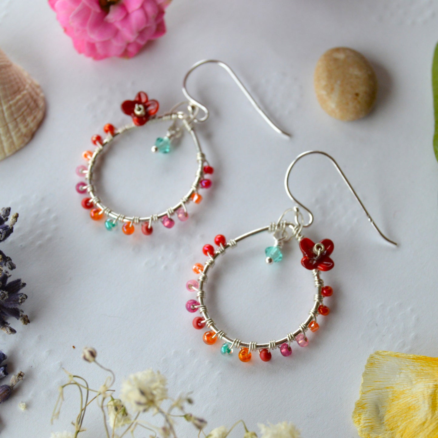 Delicate drop earrings in sterling silver wire-wrapped with Czech glass seed beads and lampwork beads crafted as flowers.