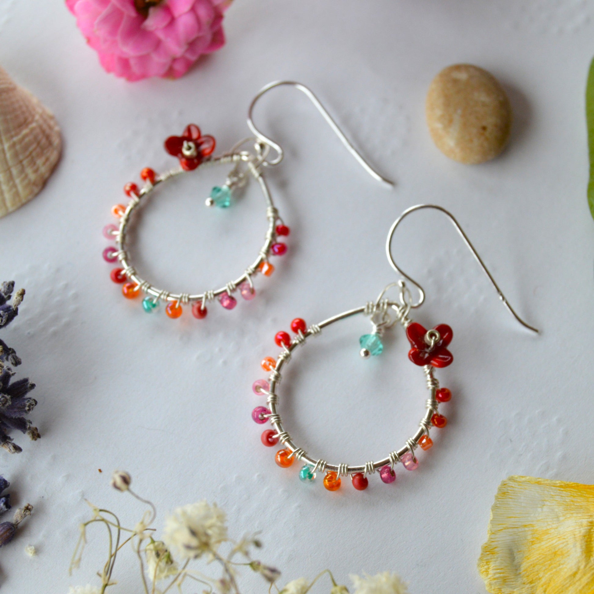 Delicate drop earrings in sterling silver wire-wrapped with Czech glass seed beads and lampwork beads crafted as flowers.