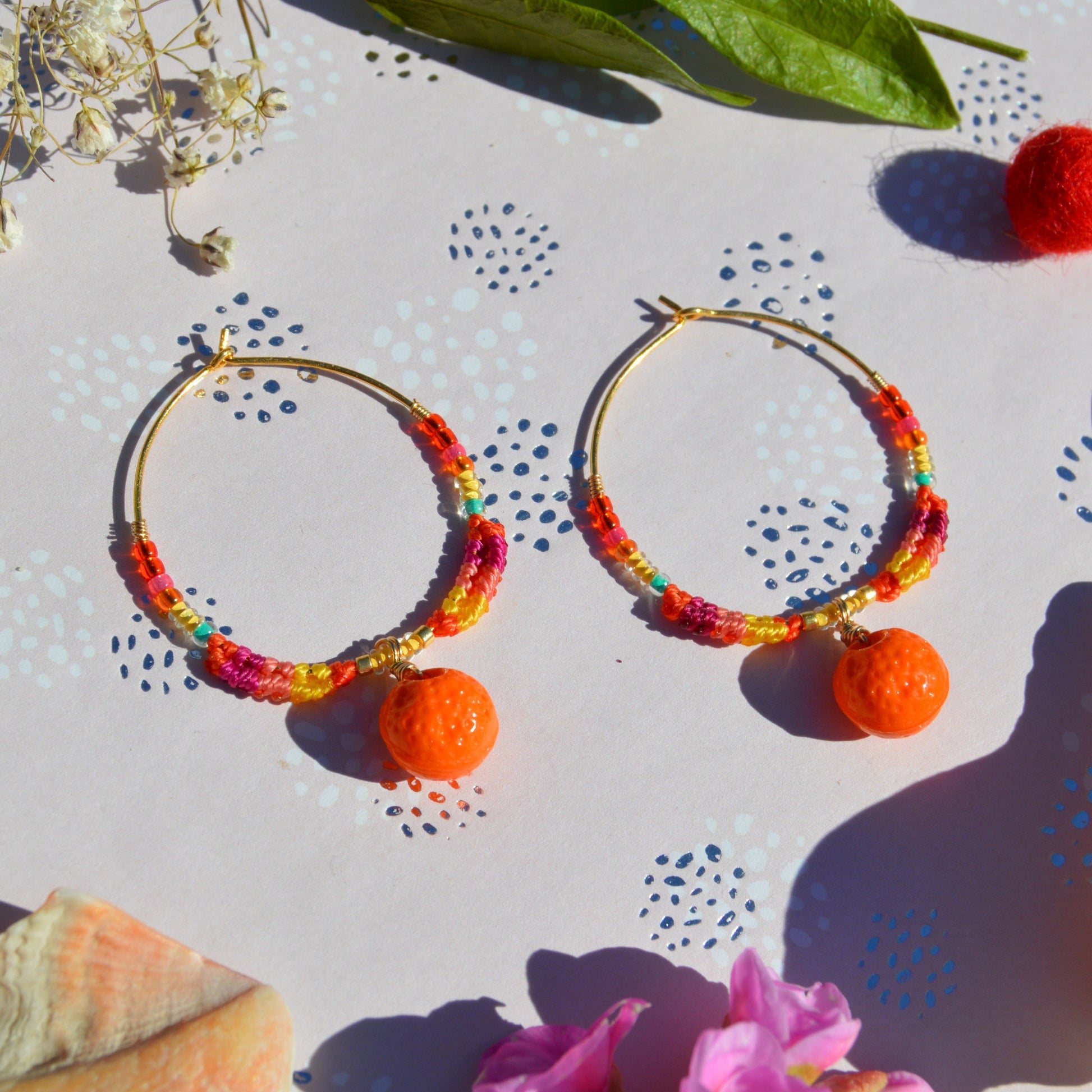 Colourful gold-plated sterling silver earrings decorated with micro macrame, Czech glass seed beads, and Czech glass orange fruit charm.