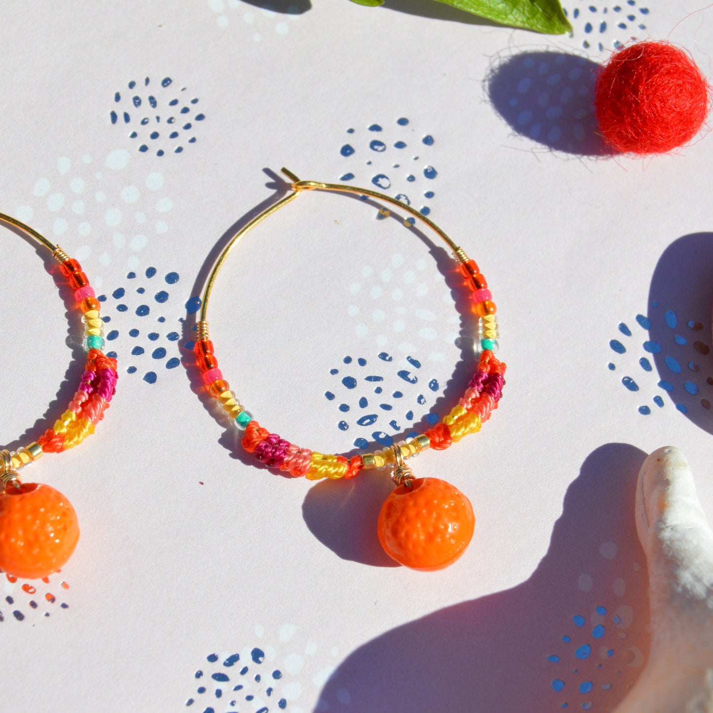 Colourful gold-plated sterling silver earrings decorated with micro macrame, Czech glass seed beads, and Czech glass orange fruit charm.