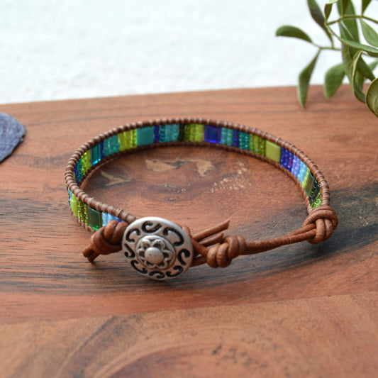 Leather wrap bracelet in green and blue tones with decorative button as a lock and extension chain in leather.
