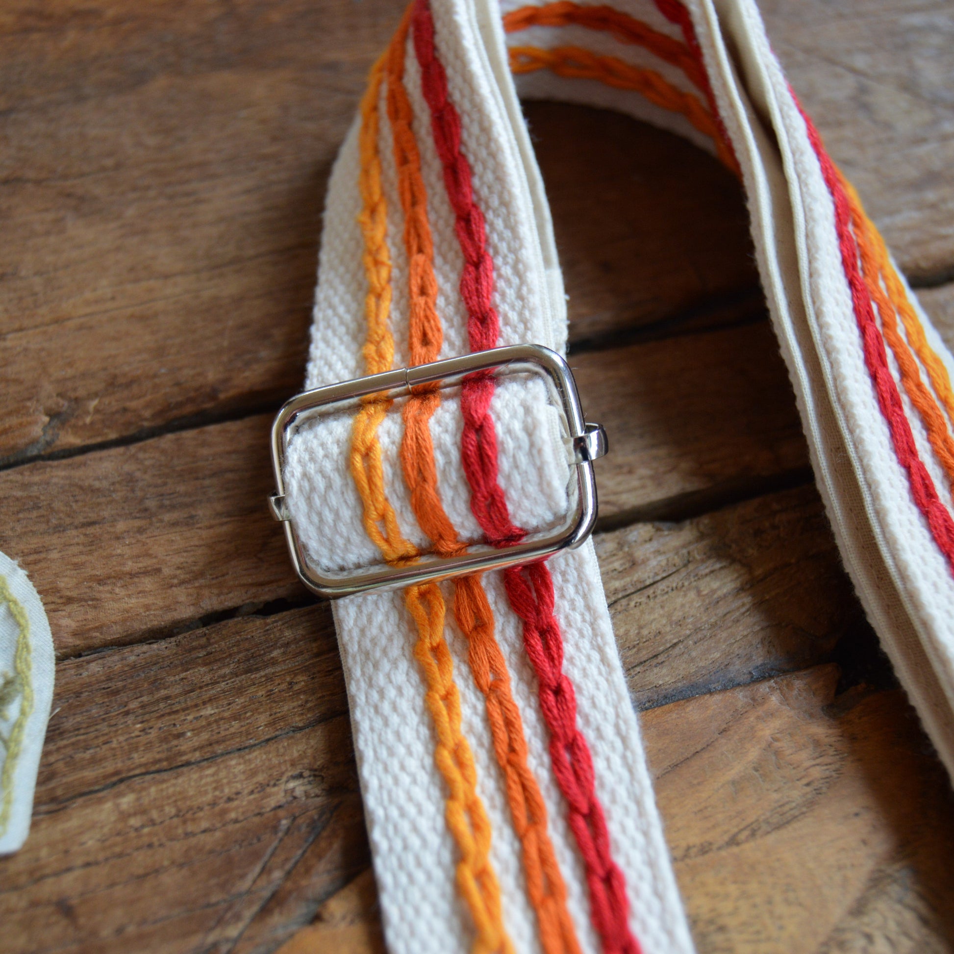 Adjustable handbag strap in red and orange tones.