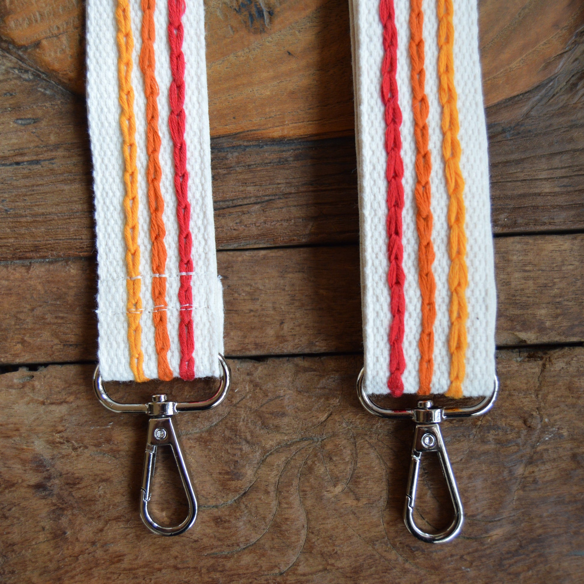 Adjustable handbag strap in red and orange tones.