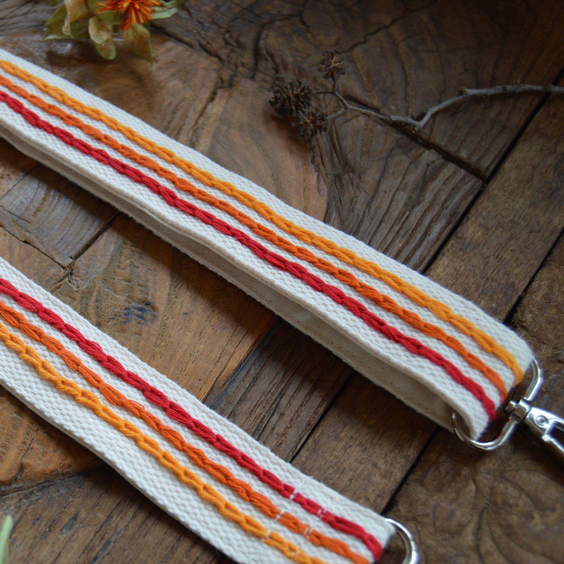Adjustable handbag strap in red and orange tones.