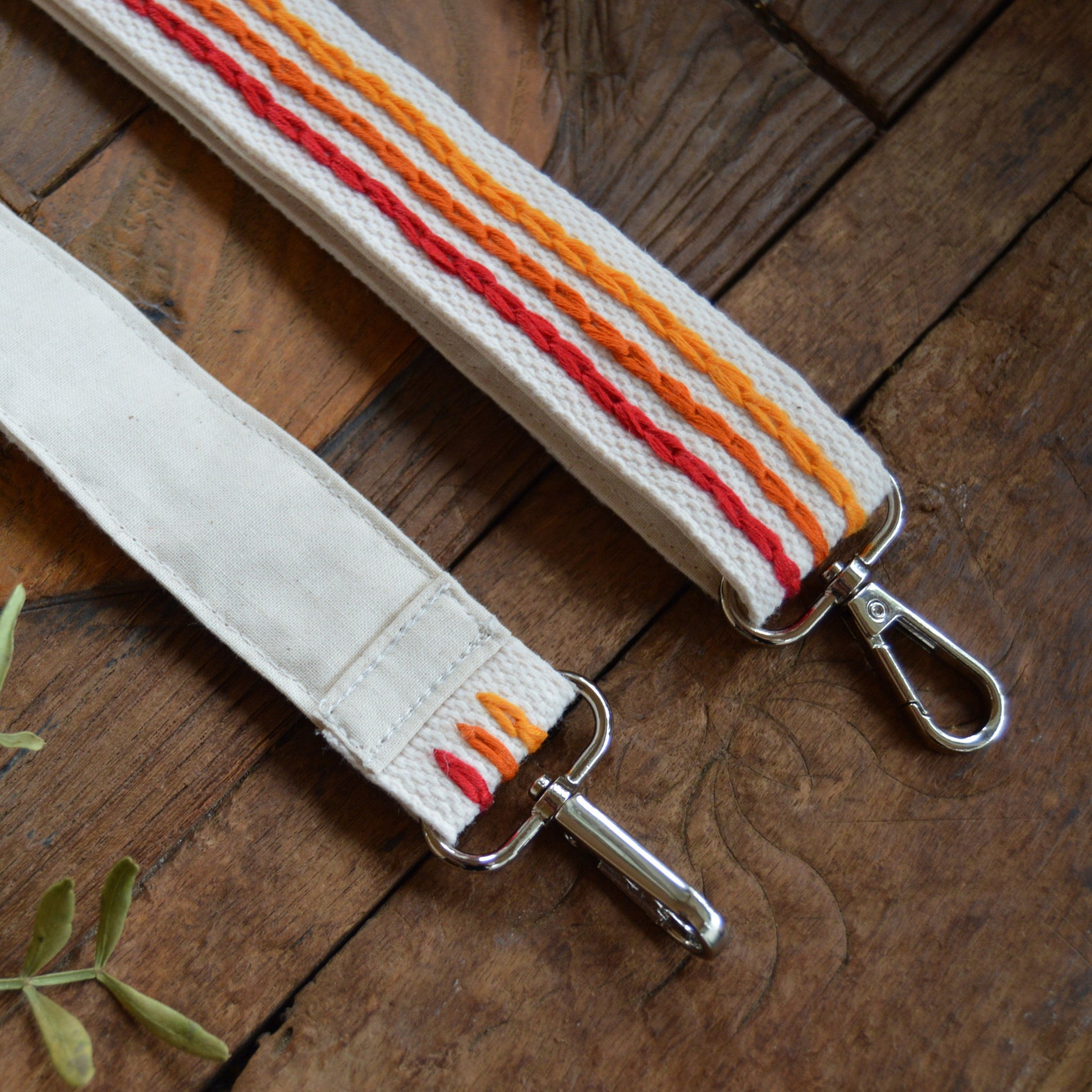 Adjustable handbag strap in red and orange tones.