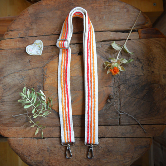 Adjustable handbag strap in red and orange tones.