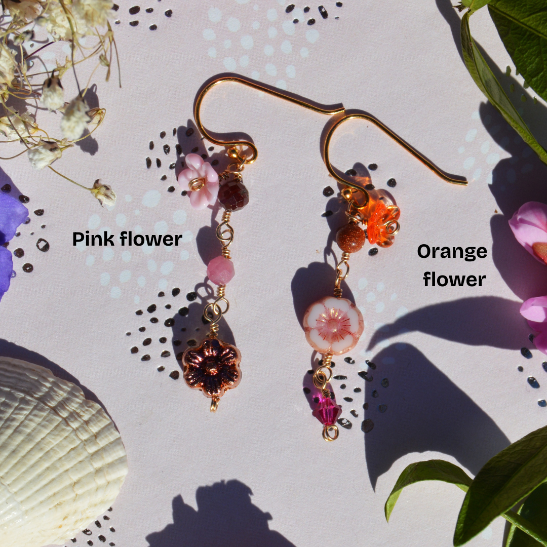 Gold-plated sterling silver earrings featuring Czech glass flowers, lampwork flowers, gemstones, and a bicone. Sold by piece.